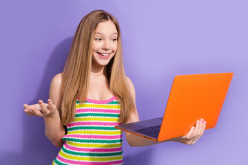 Portrait of cheerful teen girl with long hairstyle wear colorful singlet look at laptop on video call isolated on purple background