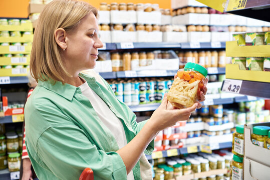 Woman buying canned vegetables in store