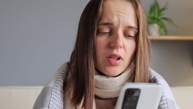 Caucasian upset frustrated sad worried woman talking mobile phone consulting with doctor by smartphone indoors having flu symptom expressing sadness.