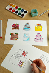 The pastry chef develops a cake design by drawing on paper. Creation of confectionery products.