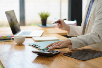 Fototapeta premium Close-up portrait of businesswoman accountant using calculator and laptop for matching financial data saving in office room, Business financial, tax, accounting concept.