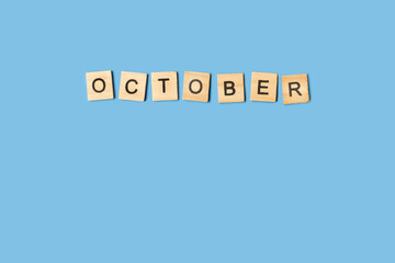  Bloques de madera formando la palabra octubre sobre un fondo celeste liso y aislado. Vista superior. Copy space