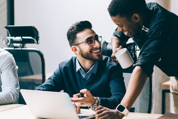 Happy excited men in formal wear communicate during coffee break in office interior
