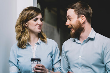 Two smiling office workers in formal wear enjoying communication during coffee break,