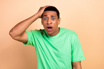 Photo portrait of handsome young guy touch head terrified dressed stylish green garment isolated on...