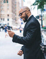 Joyful black businessman using smartphone