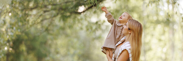 A young european woman in casual, comfortable beige clothes holding a small child in her arms in...