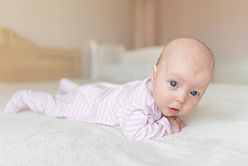 A small baby in a good mood. Baby girl lying on the bed.
