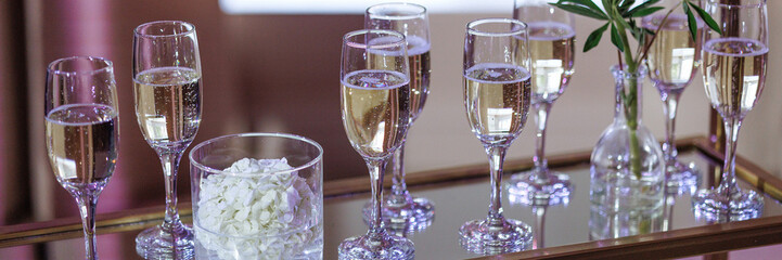 Glasses of champagne on a glass stand on a wedding buffet. A concept for celebrating a special occasion or showcasing the elegance and luxury of your catering business. Banner with copy space.