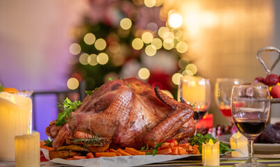 Thanksgiving dinner, Thanksgiving turkey. Served table. Christmas turkey dinner. Baked turkey garnished with red berries in front of Christmas tree and burning candles. Roasted turkey table setting