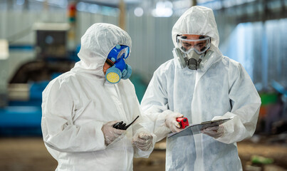 Male inspector team investigate danger chemical gas leak spill with safety face mask PPE suit in...
