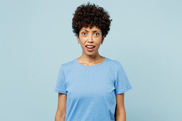 Fototapeta na wymiar Young shocked scared sad mad woman of African American ethnicity wearing t-shirt casual clothes looking camera isolated on plain pastel light blue cyan background studio portrait. Lifestyle concept.