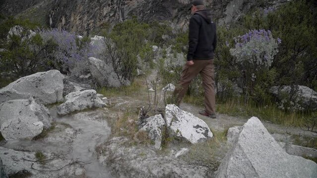 young caucasian man hiking through the mountainous landscape of the cordillera blanca in the Andes mountains of Peru near laguna Paron.