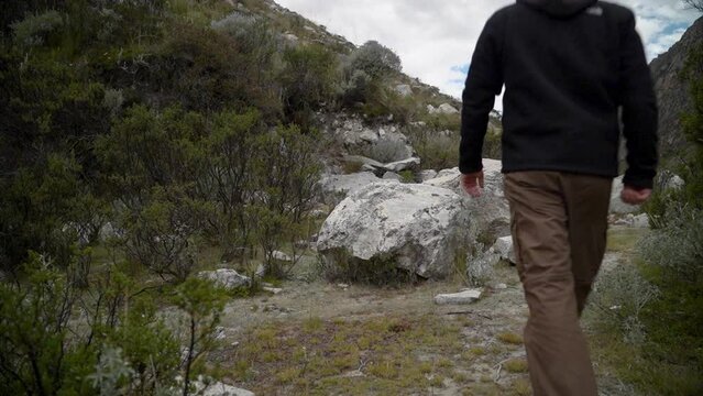 young caucasian man hiking through the mountainous landscape of the cordillera blanca in the Andes mountains of Peru near laguna Paron.