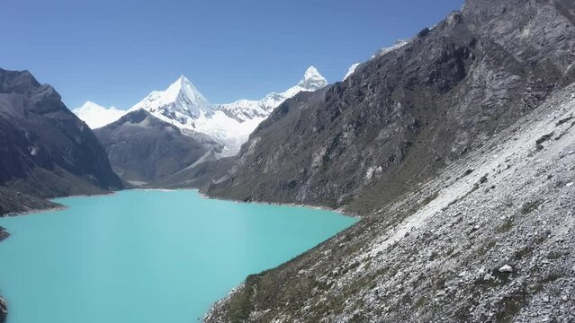 beautiful turquoise water of the lake at laguna paron lagoon in the high andes mountains of the cordillera blanca at huascaran, Peru, with snow covered mountain peaks on a bright sunny day.