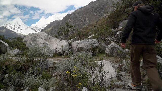 young caucasian man hiking through the mountainous landscape of the cordillera blanca in the Andes mountains of Peru near laguna Paron.
