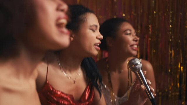 Excited female friends singing karaoke and partying, celebrating New Years eve