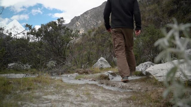 young caucasian man hiking through the mountainous landscape of the cordillera blanca in the Andes mountains of Peru near laguna Paron.