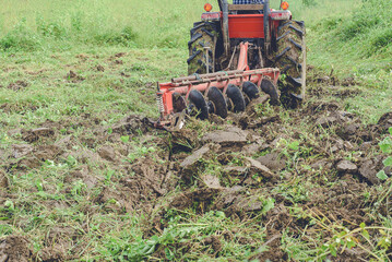 Tractor Tilling the Soil with Vibrant Green Grass Background