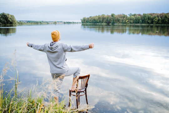 Happiness to be free, a guy standing barefoot in the water, a man in a gray suit and a yellow hat enjoying life, a wooden chair to support with his foot.