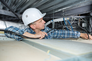 man working in ceiling with cables
