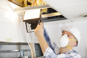 plasterer wearing dust mask while checking the ceiling