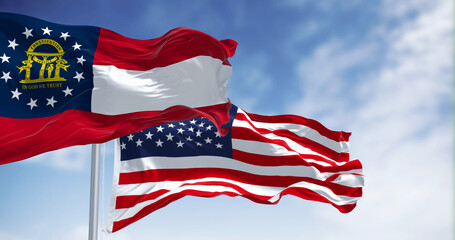 The flags of Georgia and United States waving in the wind on a clear day