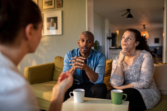 Mixed couple having a conversation with insurance saleswoman at home