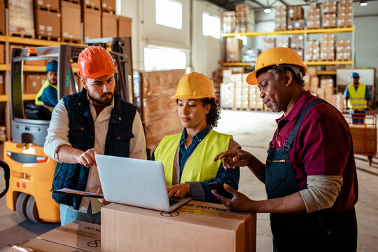 Group of diverse warehouse workers pointing at a laptop in a warehouse