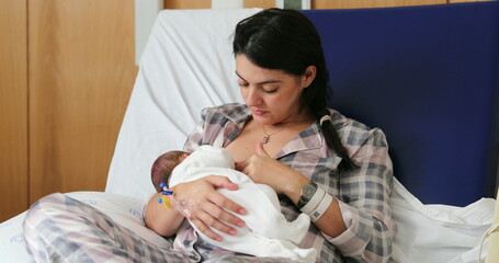 Mom breastfeeding newborn baby infant at hospital, first day of life