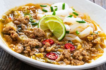 Yunnan rice noodle soup on wooden table
