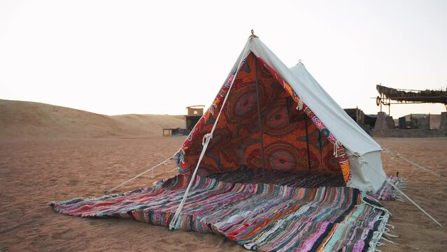 Motion forward inside fabric tent with colorful pattern carpet in the bedouin camp. Tourist excursion sleep at night in the desert