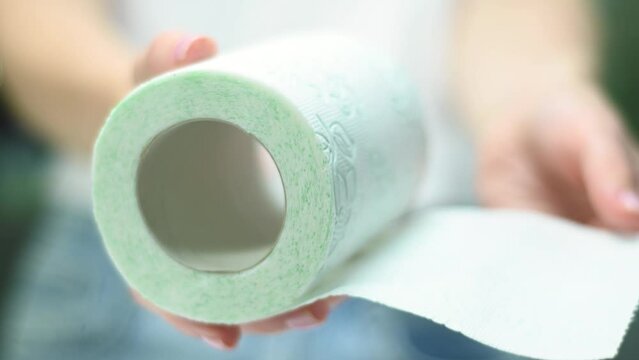 Woman showing roll toilet paper close up, blur background