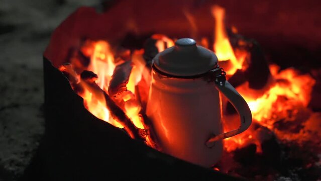 Close up of metal kettle on coals in a campfire. Brew bedouin tea in the desert at night