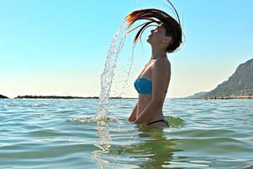 Beautiful woman jumps out of the sea with a big splash