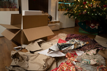 It's Christmas Eve. The presents have been unwrapped. In the Christmas living room there is a chaos of wrapping paper and boxes under the Christmas tree. Authentic image from private party. - obrazy, fototapety, plakaty