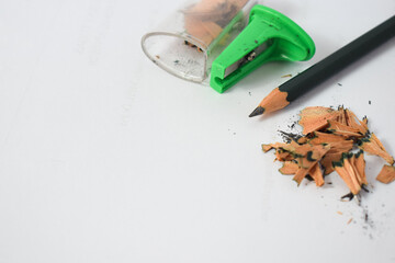 green pencil sharpener and dark green pencils, pencil shavings on white background