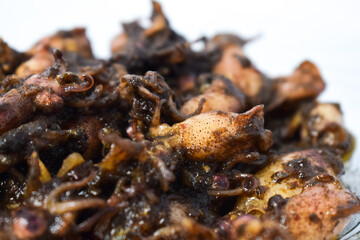 Close up Tumis Cumi, Oseng cumi or Stir Fried Squid placed on tranparent plate of glass isolated on white background. Indonesian food 