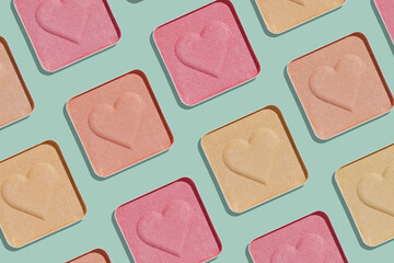 Minimal pattern compact eye shadow glitter swatches on trend green background, pastel color photo, eyeshadow with heart imprint, beige pink colored powder makeup, square pack, cosmetic texture