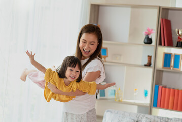 Mother having fun and playing with her daughter at home, family concept