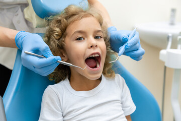 dentist, doctor examines the oral cavity of a little girl, uses a mouth mirror, baby teeth...