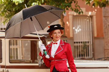 Mujer vestida de Mary Poppins con paraguas junto a coche retro en la feria modernista Novelda 2023