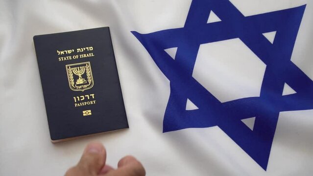 Man's hand puts Israeli international passports onto the Israeli flag