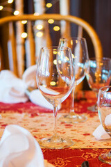 Elegant Dining Table Set-Up with Two Empty Wine Glasses, One in Focus and String Light Bokeh in Background