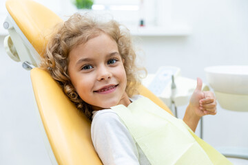 Happy little girl having dentist's appointment in modern clinic. Little patient, adorable little child girl sitting in dentist's chair during appointment in pediatric dentistry clinic