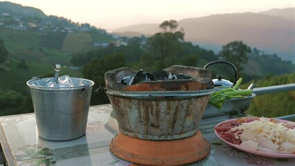 Sizzling charcoal on a barbecue grill, set against a stunning mountain sunset. Backdrop for a delicious and nutritious meal.