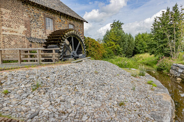 Stone building with old Eper or Wingbergermolen water mill next to Geul river, two windows, trees...
