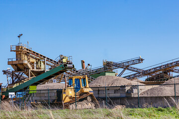 Gravel, sand and earth extraction work site, heavy industrial extraction machinery, belt conveyor, crusher and gravel sorting, blue sky in background, sunny day in Meers, Elsloo, Netherlands