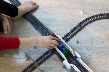 Top view of a child playing with a children's railway. Children's Train and Little Hands