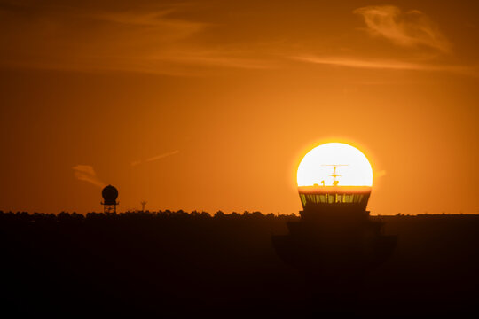 The sun aligned at sunrise with an airport control tower, Spain
